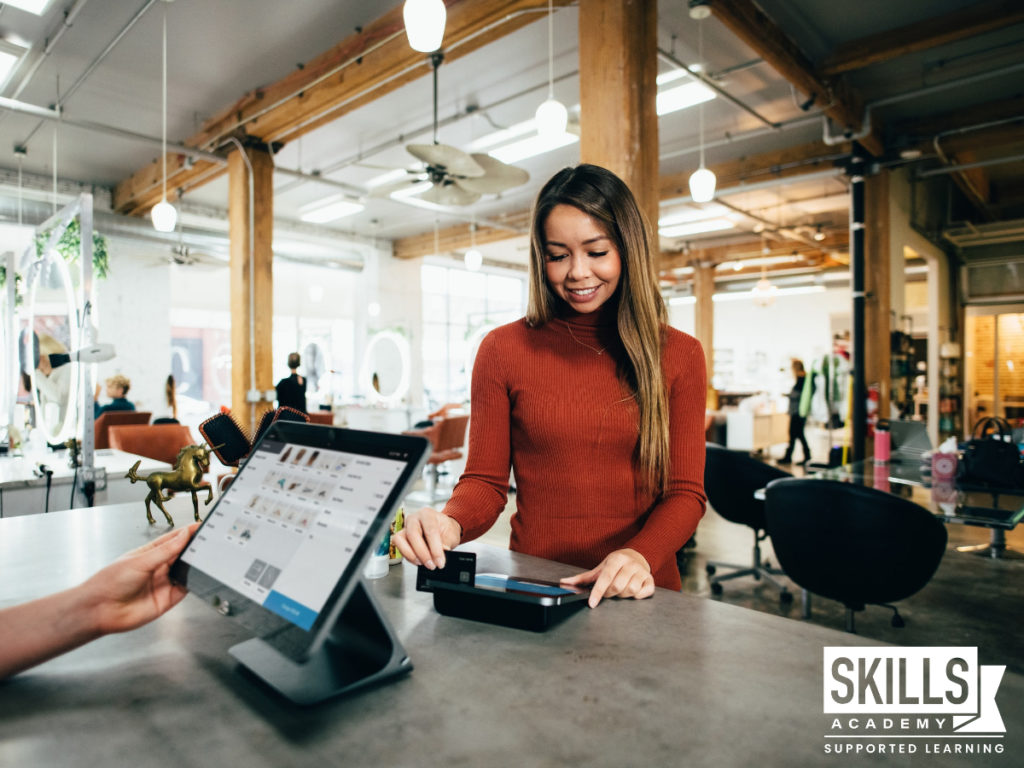 Customer standing at the cashier, making a payment. Learn how to provide excellent customer service with our Customer Relations Management Courses.