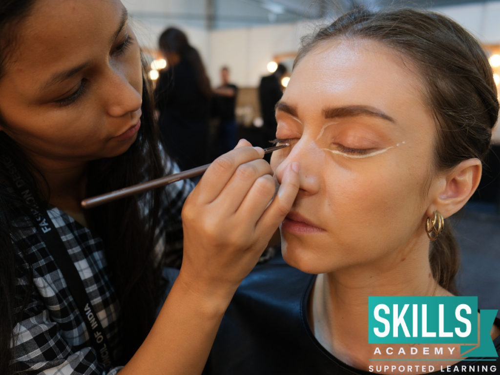 Young make-up artist putting make-up on model backstage at a fashion show. You can live the dream with our Make-Up Courses.