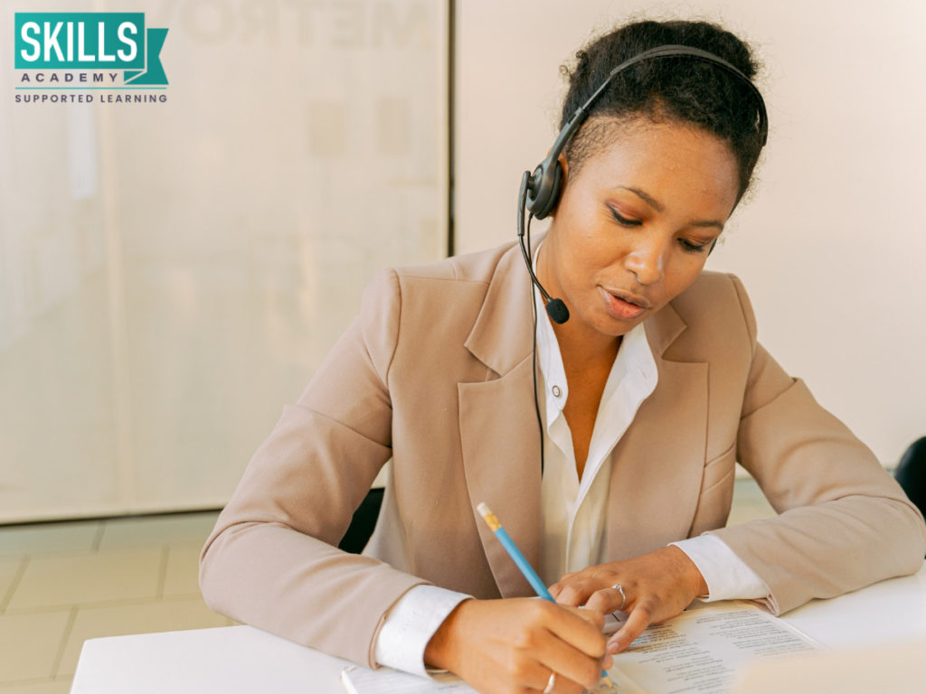 Secretary talking on the phone while making notes. Learn top admin skills with our Secretarial Courses.