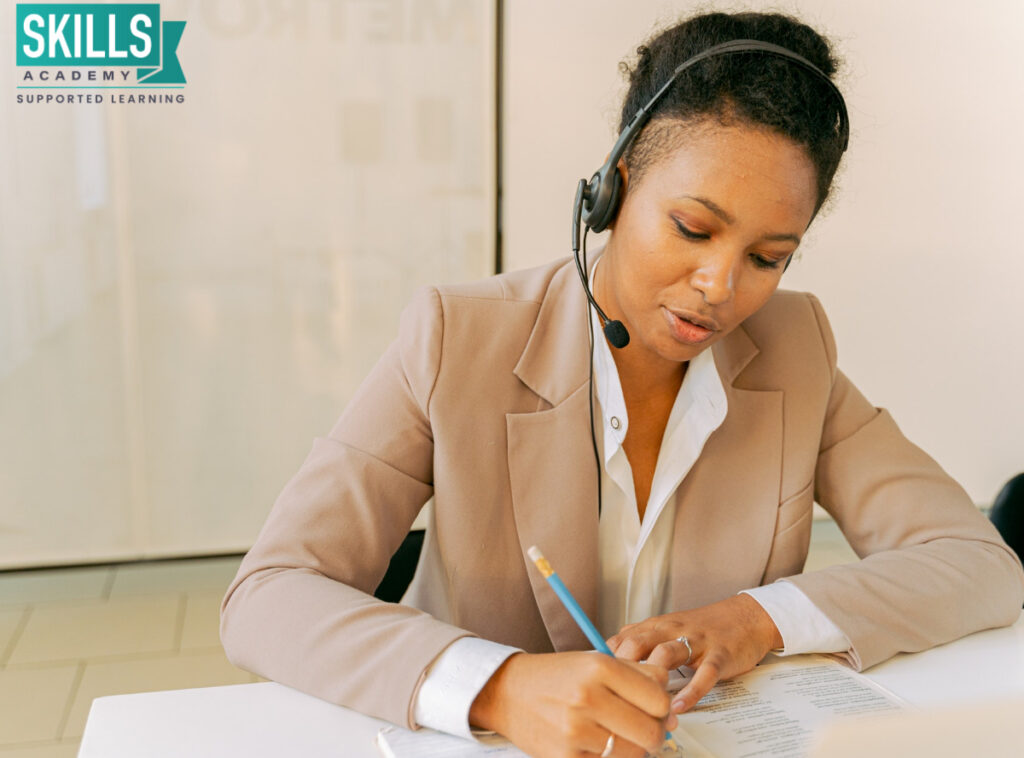 Secretary talking on the phone while making notes. Learn top admin skills with our Secretarial Courses.