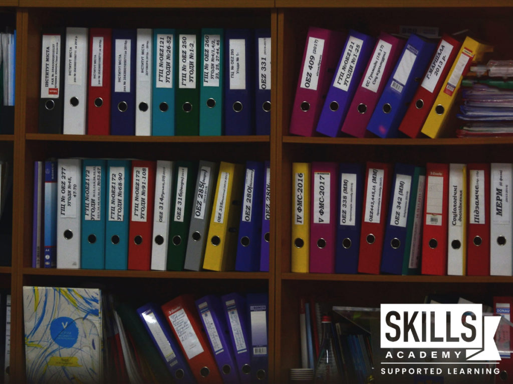 Files stacked in a bookcase. Learn organisational skills and more with our Medical Receptionist Courses