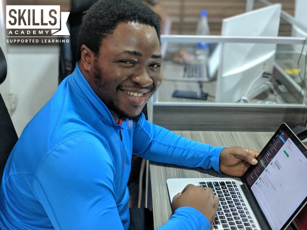 Man with a blue shirt working in front of a laptop uses the skills he learnt in our Small Business Management Courses.