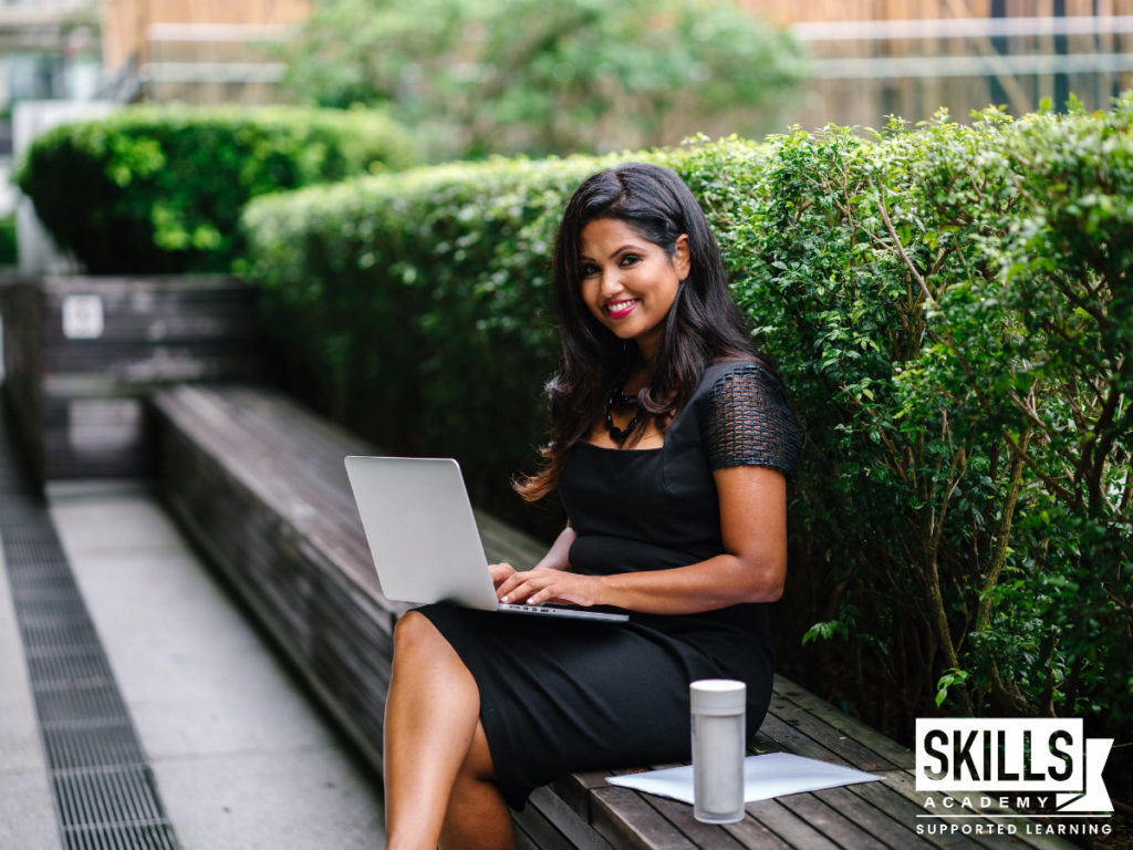 A student sitting on a bench with her laptop waiting for her CIMA Exam Results