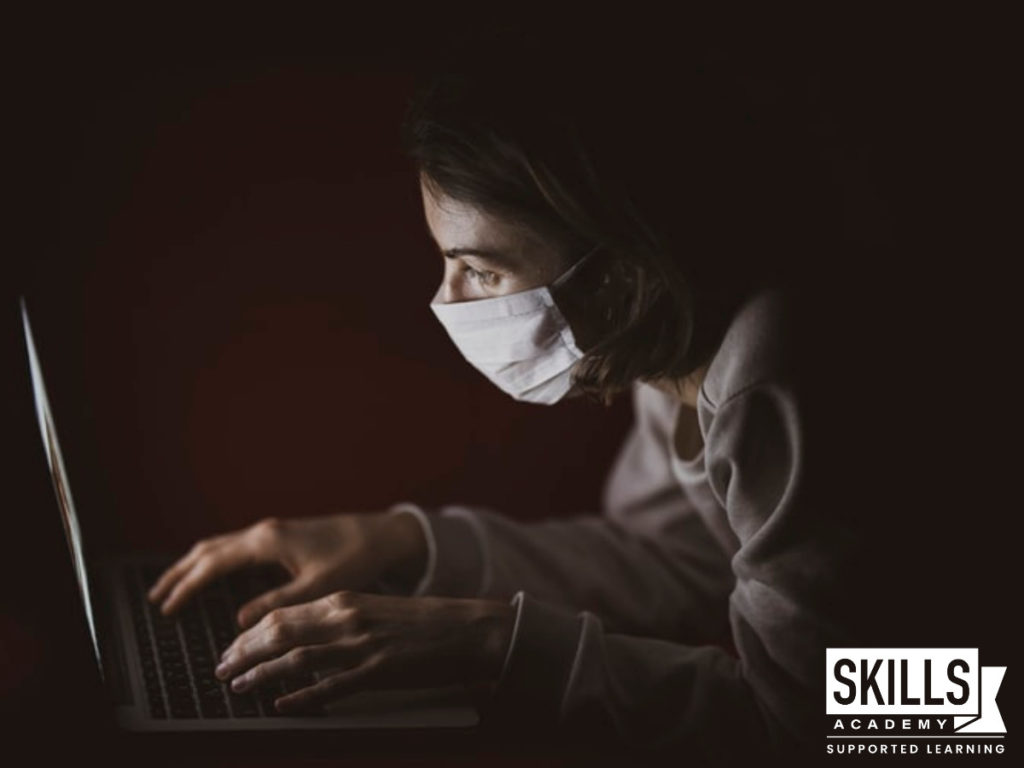 Student wearing a mask while typing on a laptop