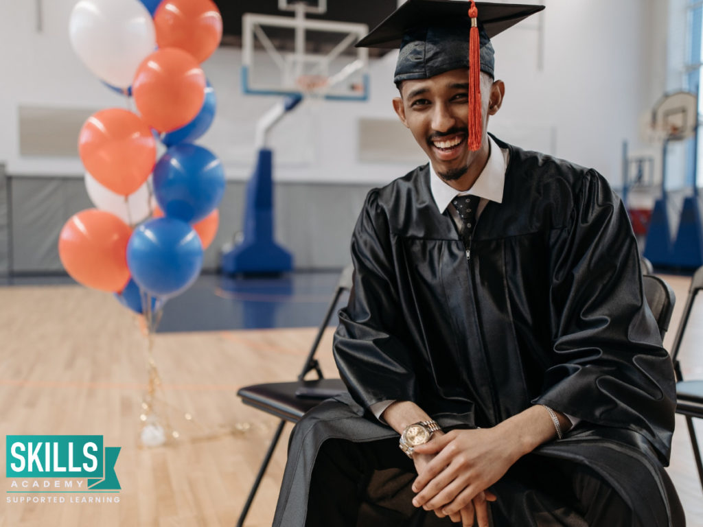 Graduate sitting in a gymnasium wearing graduate attire after completing our Diploma Courses.
