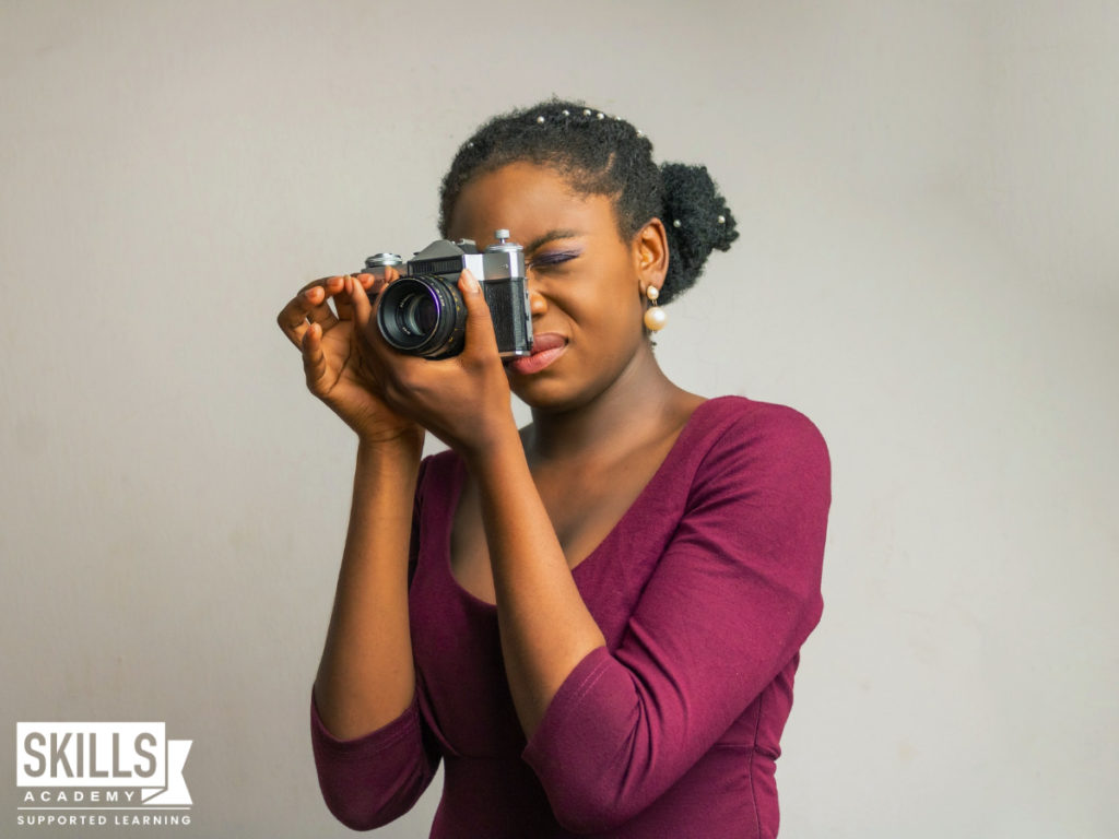 Woman taking a photo with a digital camera using the skills she gained in our Interior Decorating Design and Photography Courses.