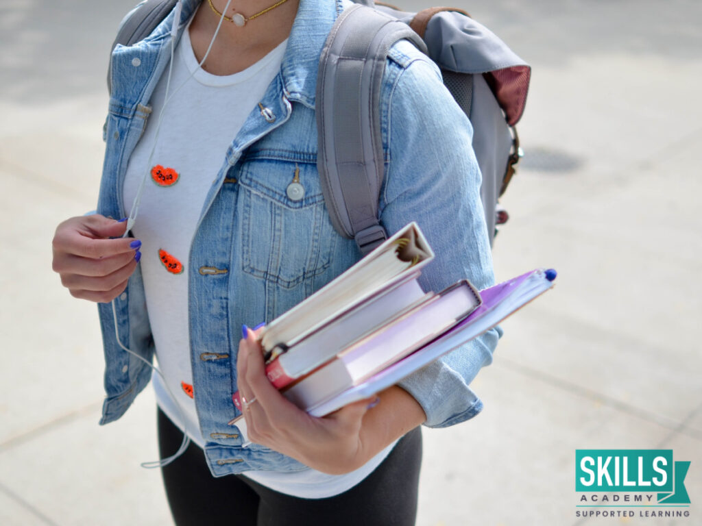 Girl wearing a backpack and carrying textbooks in her hand. Find out all you need to know about the registration requirements at Skills Academy.