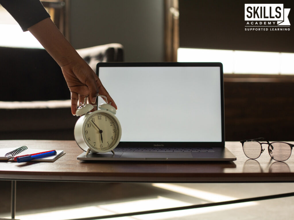 A person holding an alarm clock on top of a laptop. Study our Short Courses today.