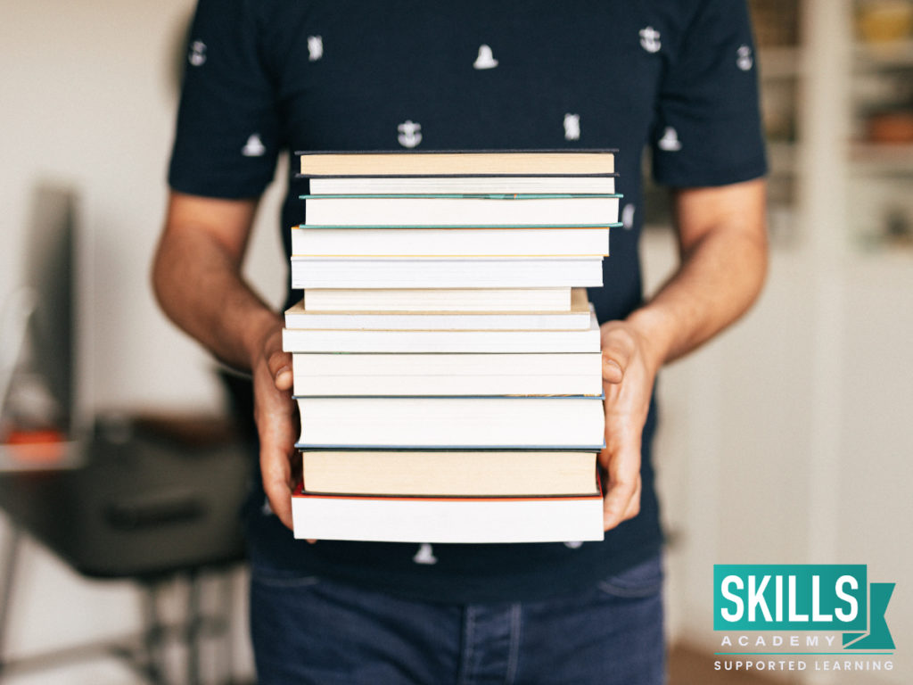 Student holding the textbooks he used to study for his final exams. Learn how to get your Matric Results 2020 Gauteng right here.