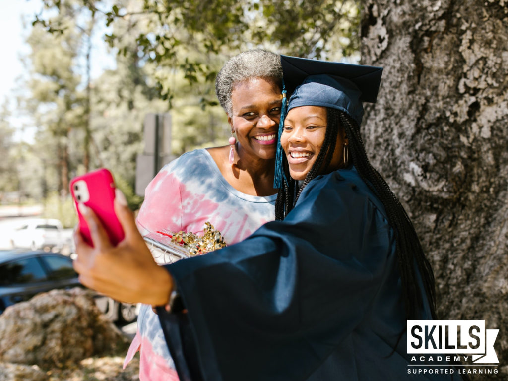 Girl in graduation cap and gown taking a picture with her mother. Get your matric with us.