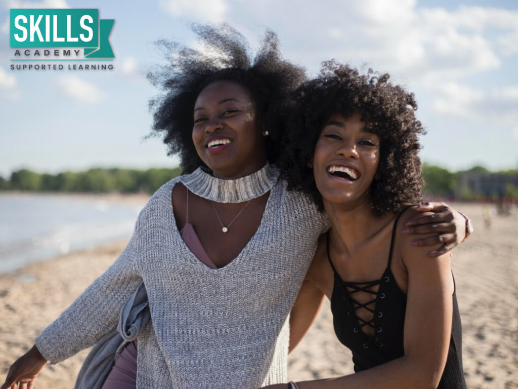 Two friends smiling on the beach. Who wins between Gap Year Vs Studying Further? You can have both when you choose Distance Learning.