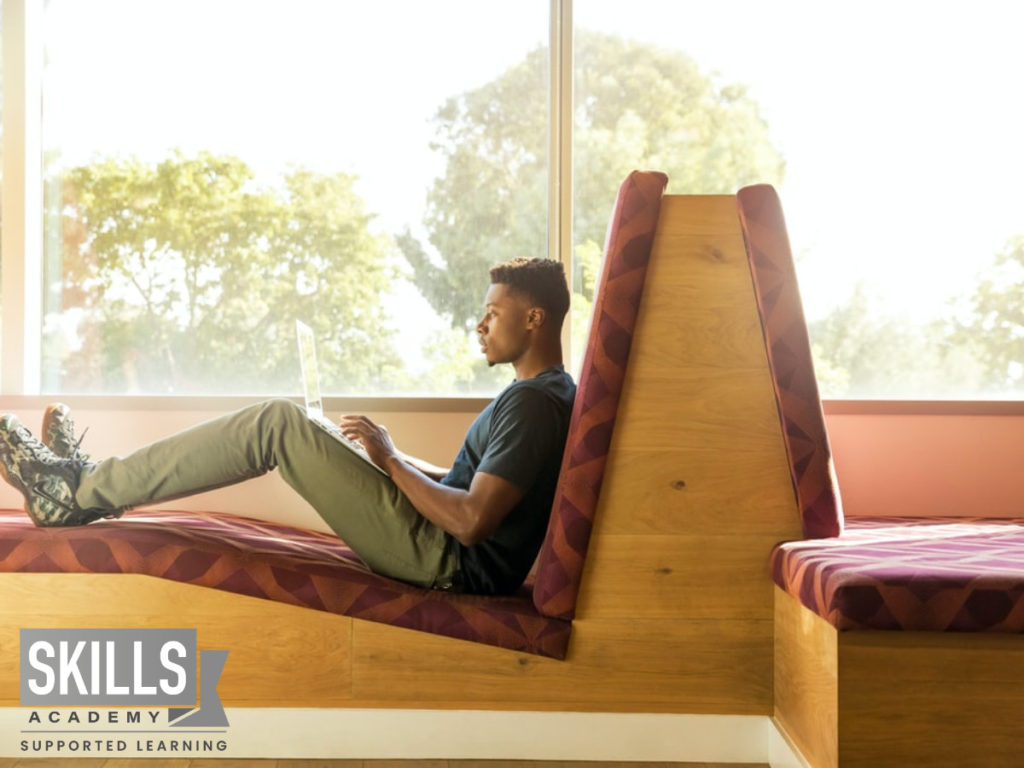 A young man sitting on a couch doing some research on the future of education