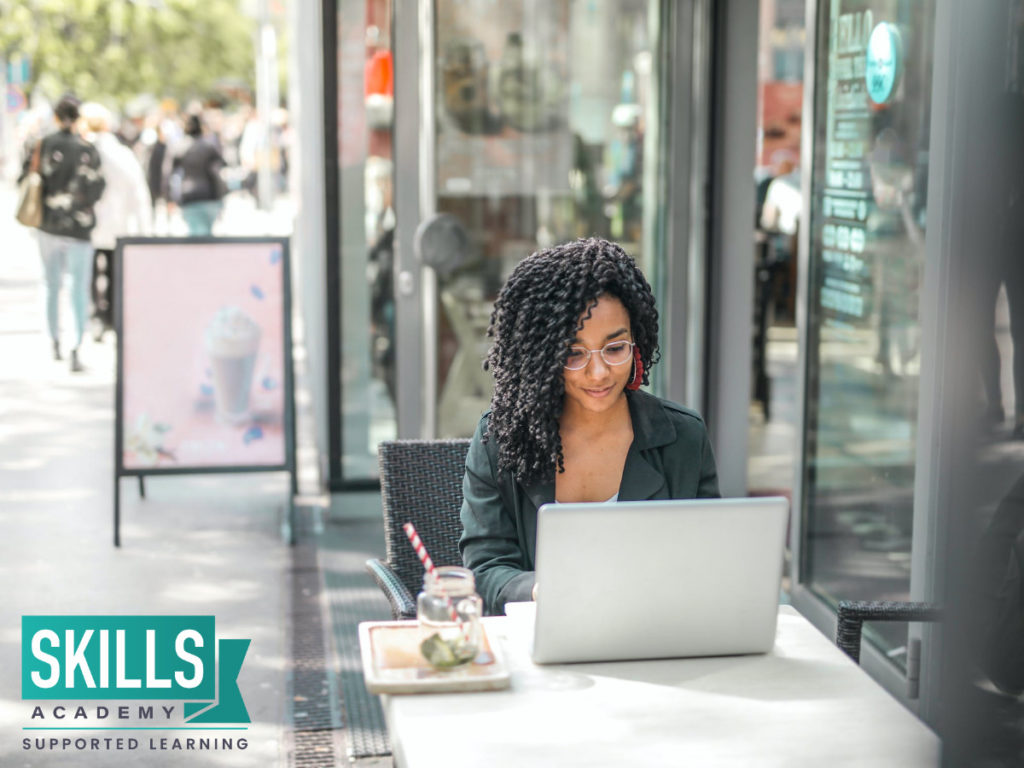 A young lady sitting outside a coffee shop with her laptop searching How Effective is Distance Learning.