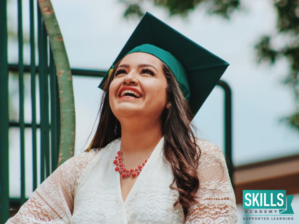 A graduated student beautifully dressed in white smiling up at the sky because having Tips on Getting Into the Beauty Industry helped her choose a career path.