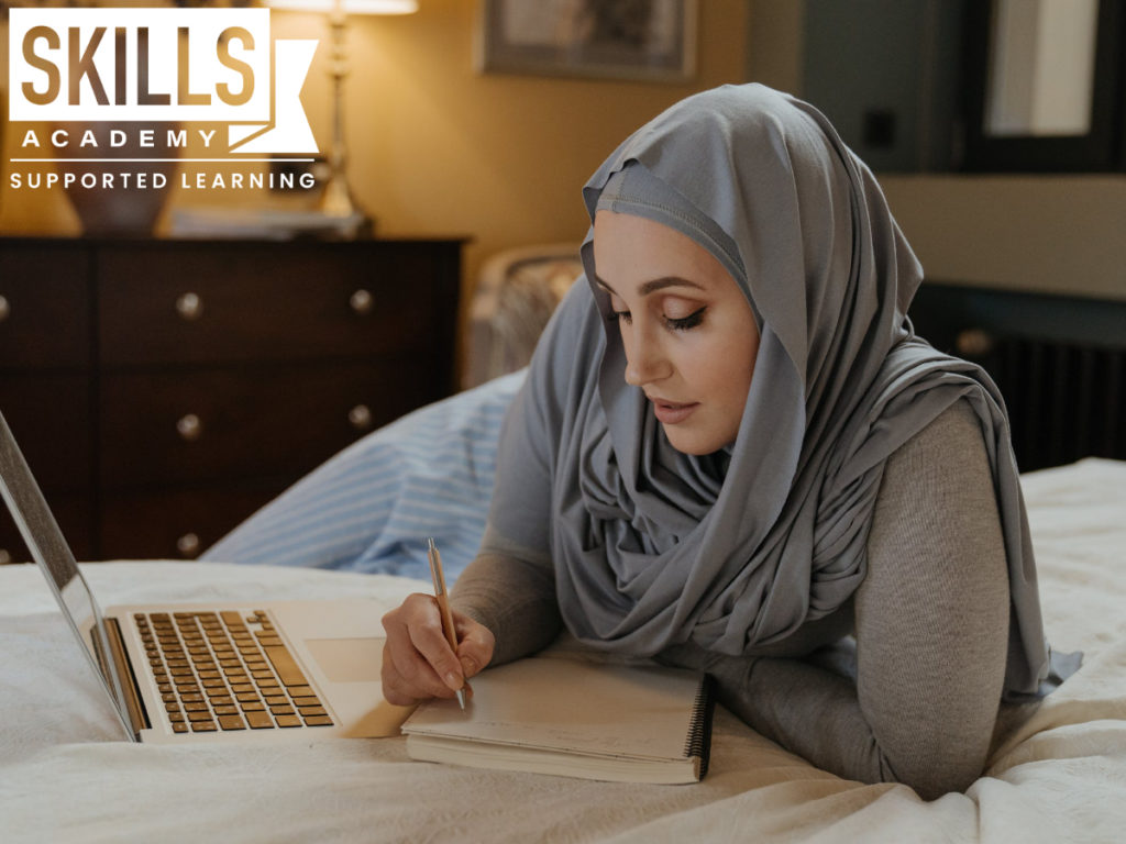 Student wearing hijab sitting in her room doing her homework. Here's how to stay motivated while doing distance learning
