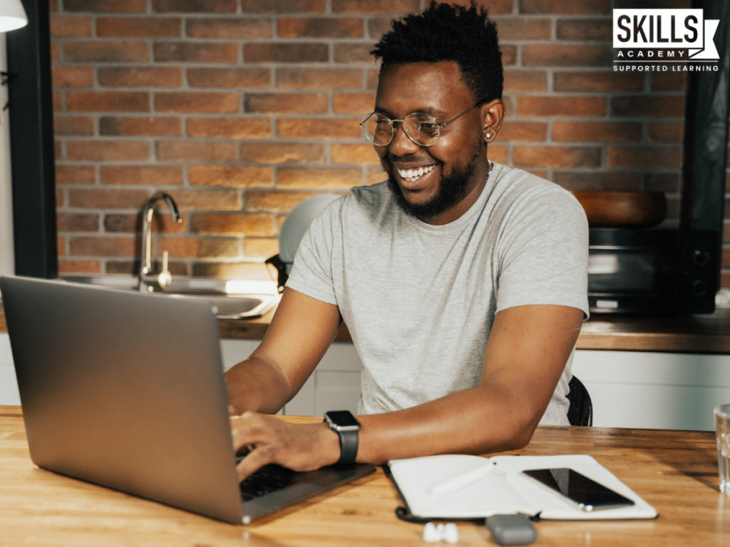 Man smiling while using a laptop. Reach your study goals with Online Tools to Help you With Your Course