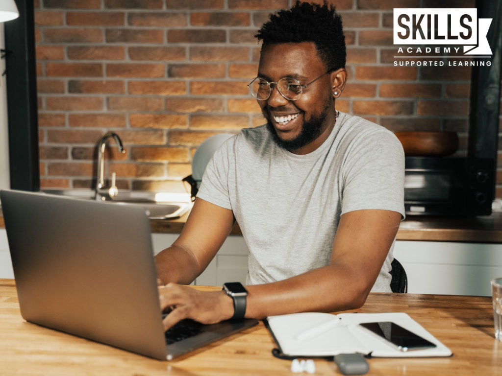 Man working on a computer while smiling as he is about to search How to set Goal for the New Year so he can plan his New Years Resolutions.