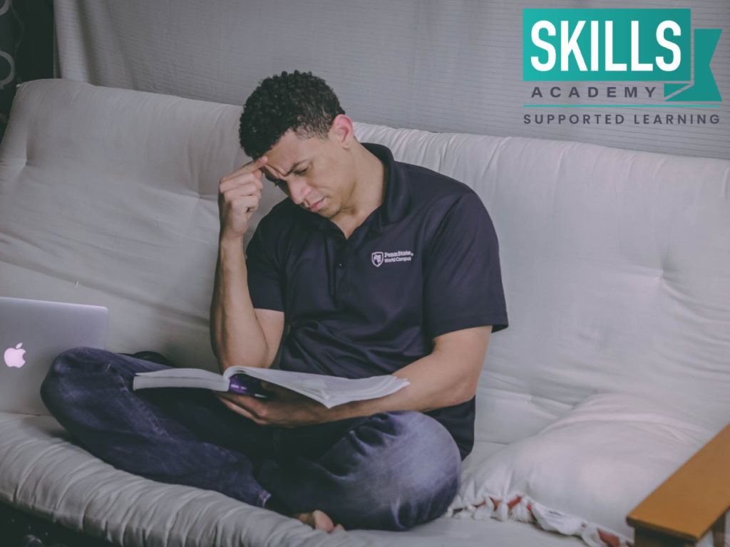 Student on the couch reading through a textbook. Wondering How to Stay Motivated While Doing Distance Learning? Here's how you can