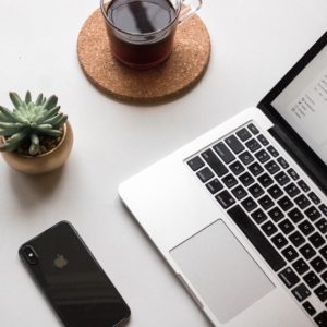 A laptop, Iphone, cup of coffee and plant on a desk. Every professional needs Basic Computer Skills for a Successful Career. Enrol into our computer courses and get a head start!