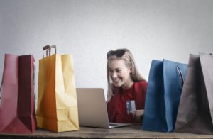 Smiling woman with shopping bags. Find ideas for Side Hustles That Will Earn you Money this Festive Season here.