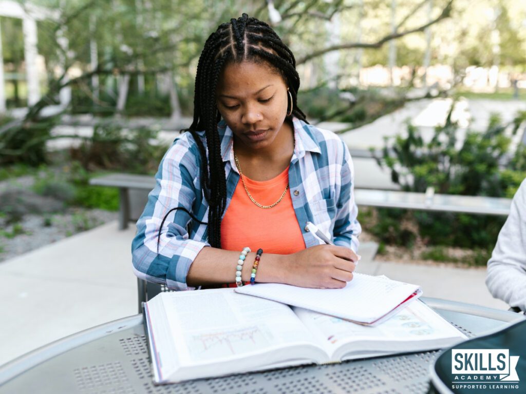 Student sitting outside writing down notes. Learn how to choose a course right here.