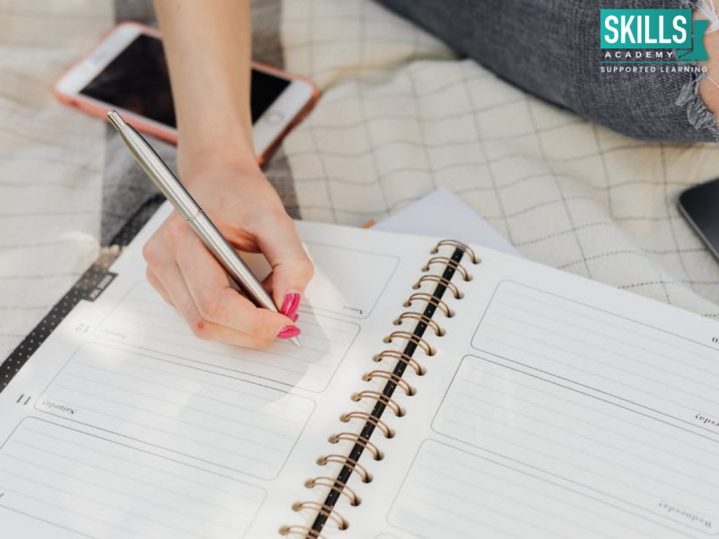 A student writing in her notebook. Find Essay Writing Tips here.
