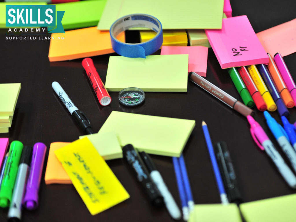Colorful sticky notes and pens scattered on a table. Sticky notes are a great tool to use when creating flashcards on How to Memorise for an Exam.