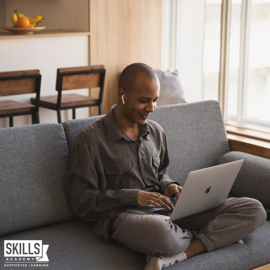 Man sitting on a couch with his laptop on his legs reading How to Prepare of we are Faced With Another Lockdown.