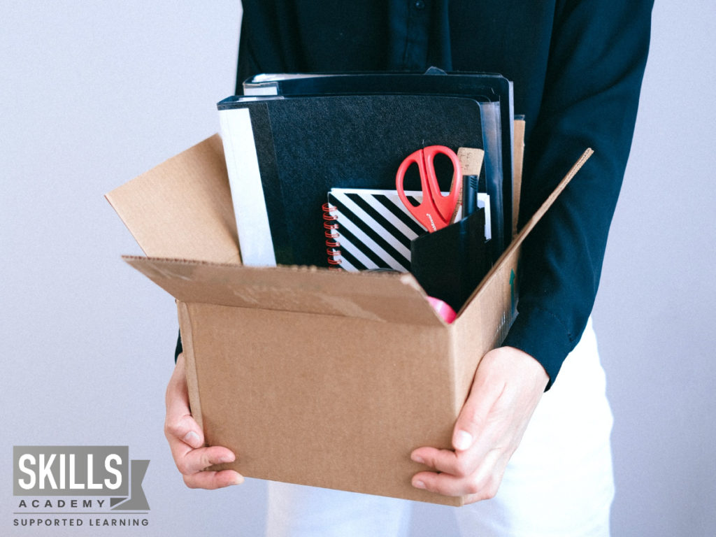 Employee holding her a books with all her work supplies after she decided to relocate for a job. Wondering if you should Relocate for a Job? Find out more right here