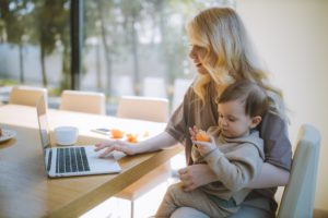 A mom with her child, using her laptop to look at Top Jobs for Working Moms