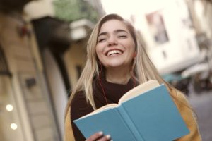 Smiling student holding a book. Reading for fun is one of the Things to do After Your Final Exams