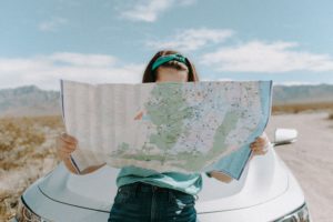 Woman looking at directions on a map during a roadtrip. Let these ideas lead you to our Tourism Business Ideas 2021 and start your own business
