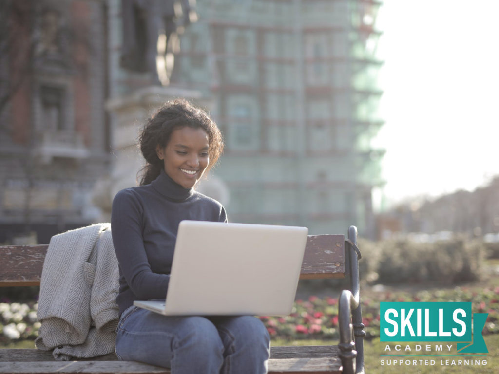 A young girl sitting in the park searching How Studying an ICB Course Will Help you get a job on her laptop.