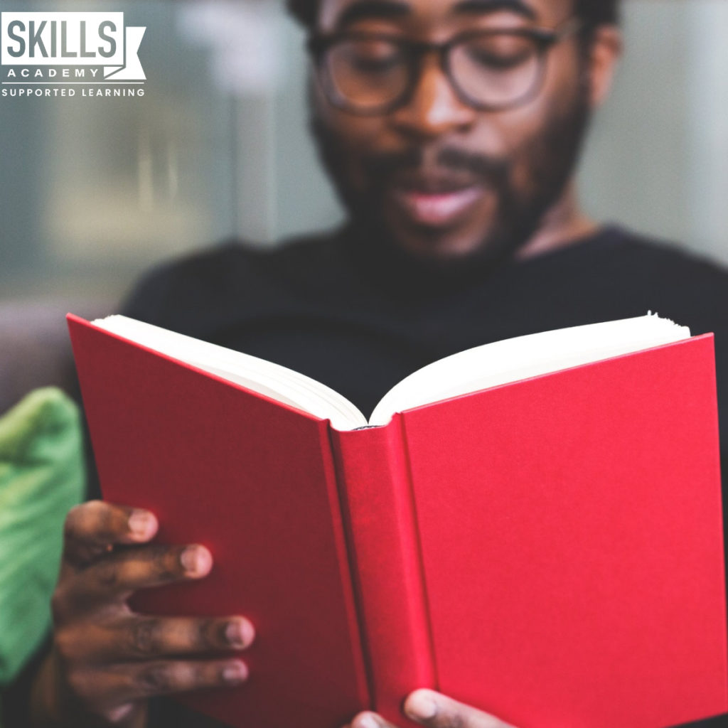 Man reading a book with a red cover. Wondering Is going back to school the right choice for you? Find out everything you need to know and more right here.