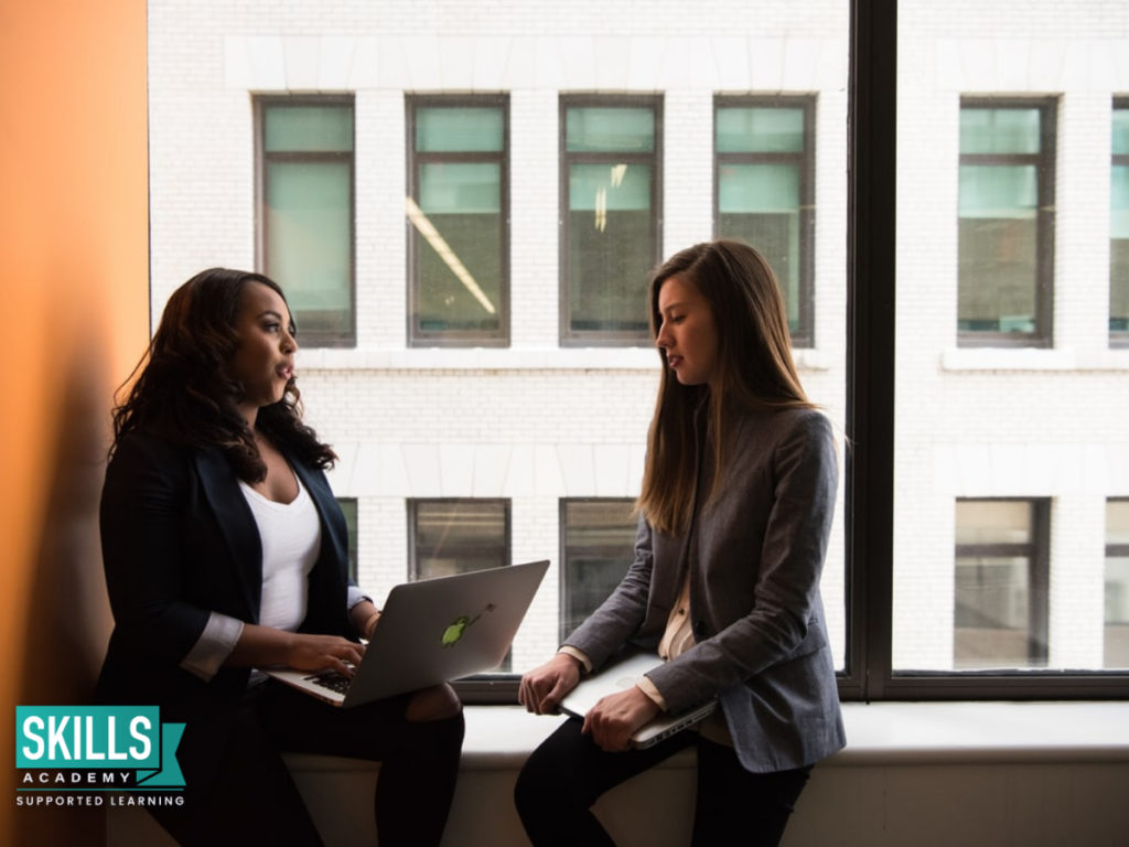A mentor and mentee sitting together discussing their goals. Find out How Becoming a Mentor can Help Your Career.