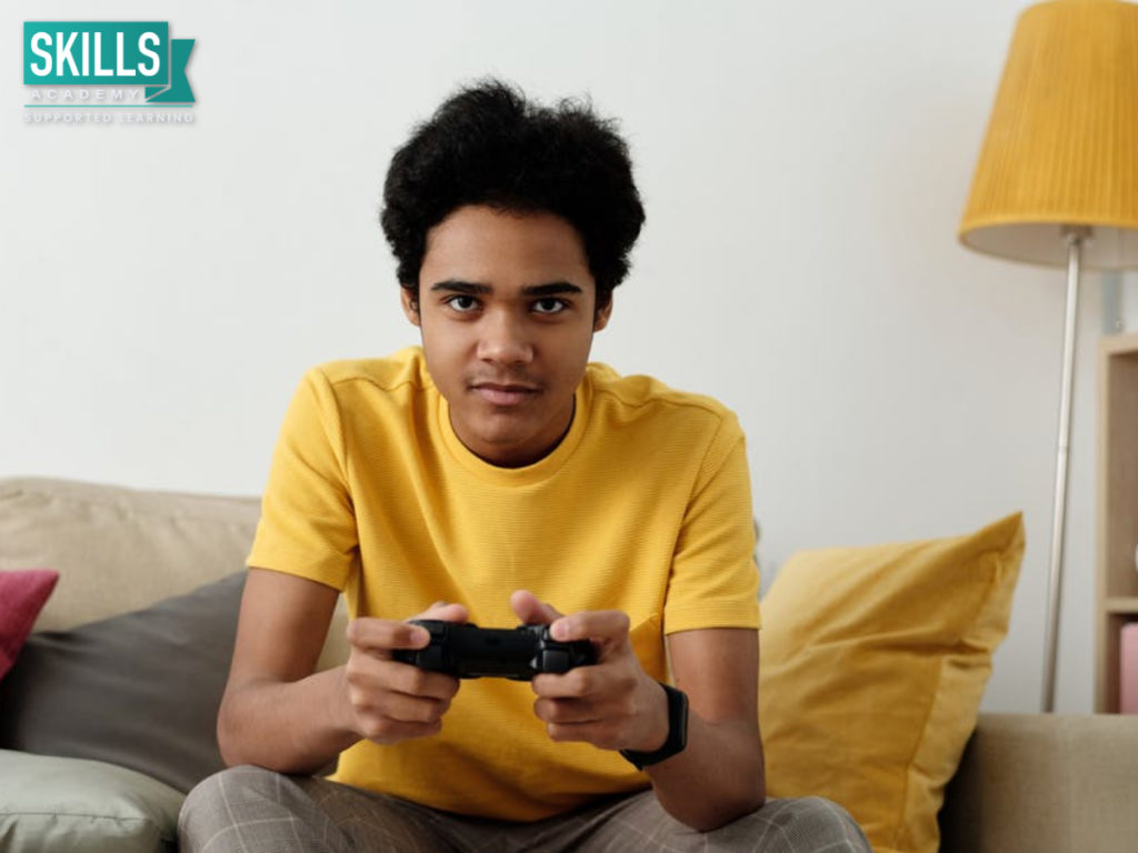 A student in a yellow shirt holding a gaming console. Find out How Video Games can Assist With Career Development here.