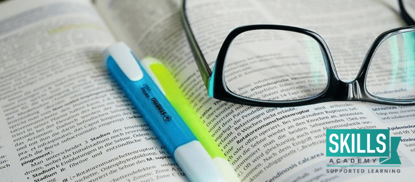 An open book with spectacles and highlighters lying on top of it