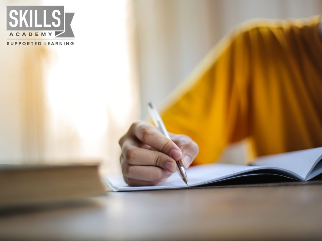 Boy wearing a yellow sweater while writing in a book and using our tips on How to Choose Subjects in Grade 10