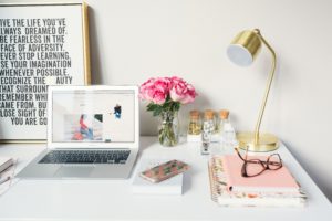 A laptop, notebooks and flowers on a white desk. Learn what to avoid in your resume with these 8 words and phrases to stop using in your resume.