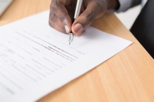 A professional holding a pen and signing a job contract. Need help Understanding job Contracts? Get all the details here.