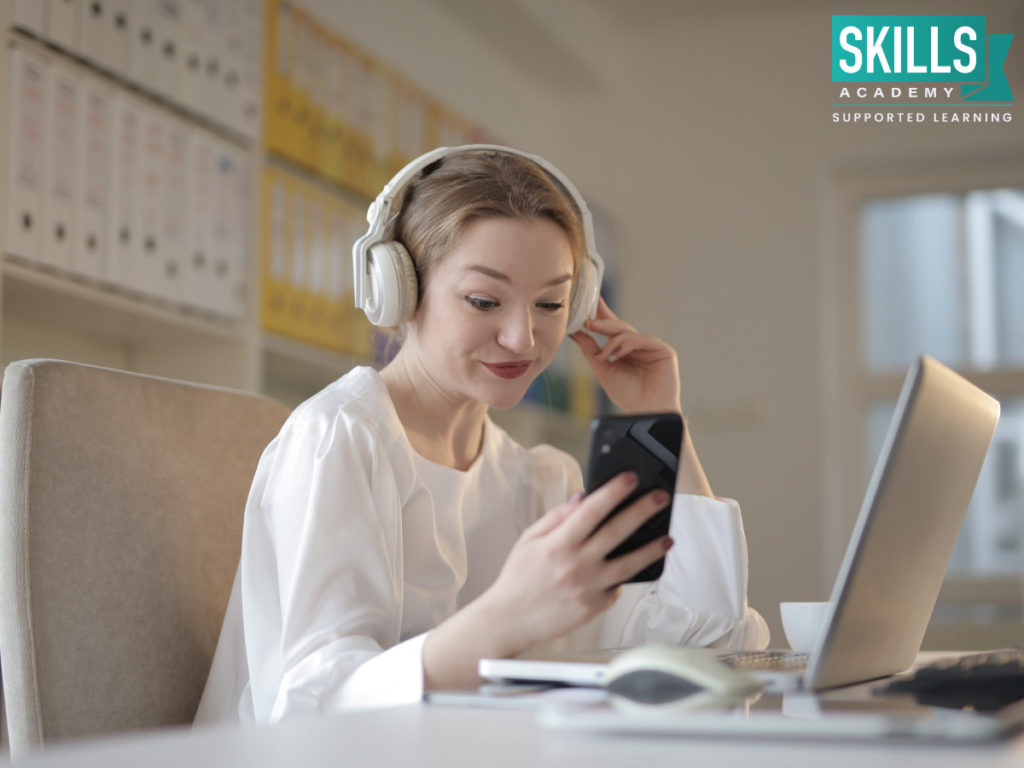 Young woman wearing headphones and playing on her phone. Find tips on How to Break Bad Work Habits right here.