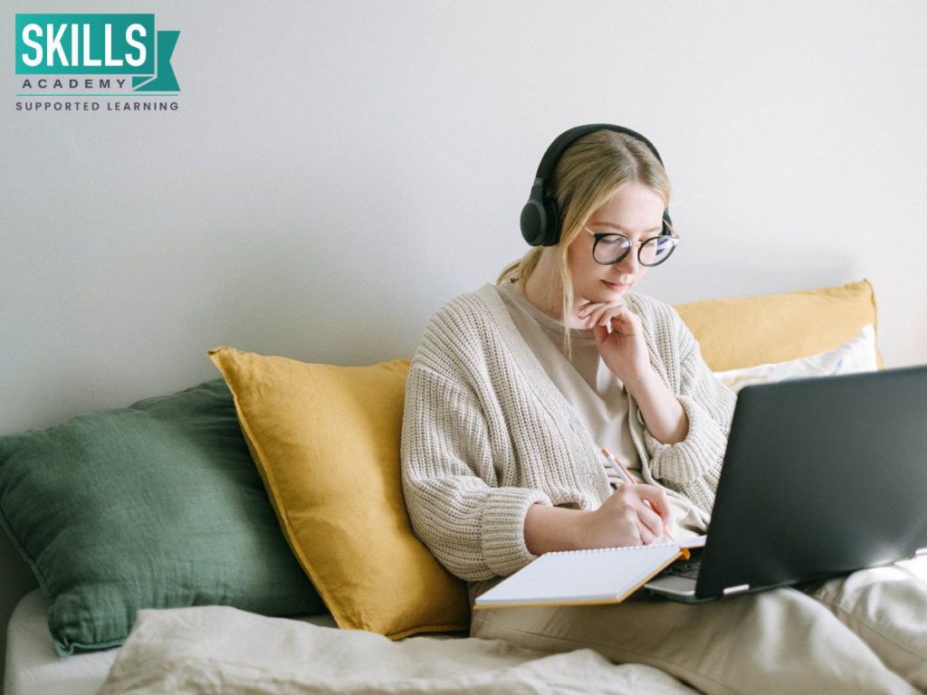 Blonde girl wearing headphones, sitting with her laptop. Find tips on How to Improve Your Writing Skills here.