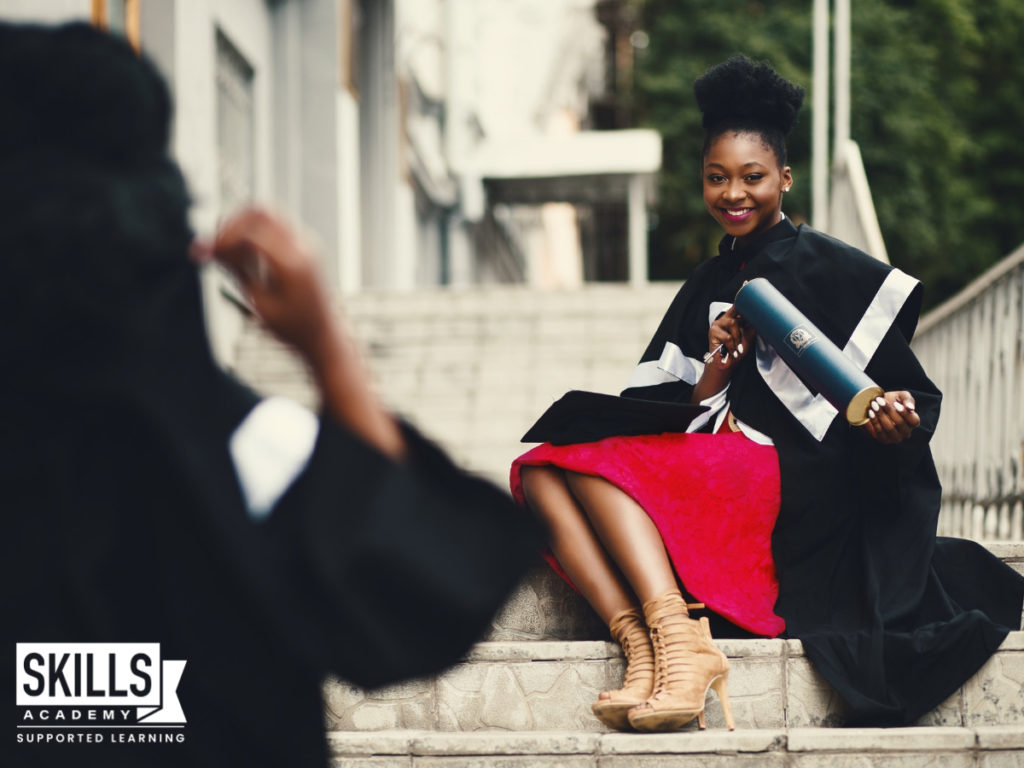 Graduate sitting on the steps of a college holding her diploma after completing her Postgraduate Studies.