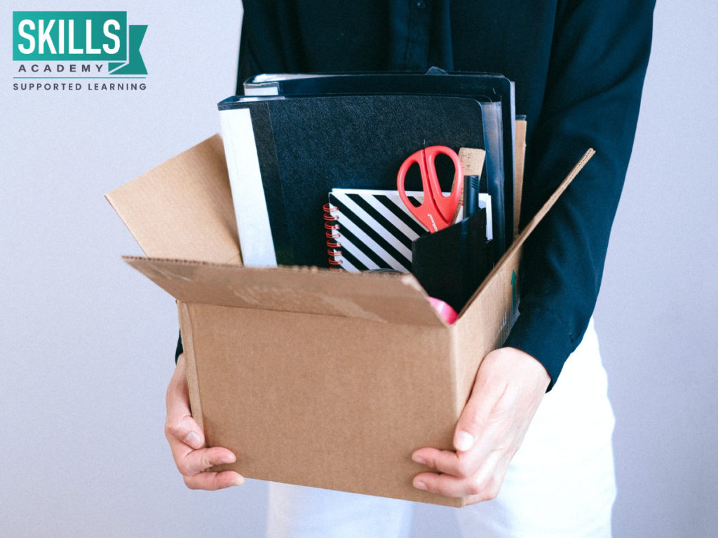 Worker carrying a box of personal effects after being retrenched. Learn What to do if you are Retrenched right here.