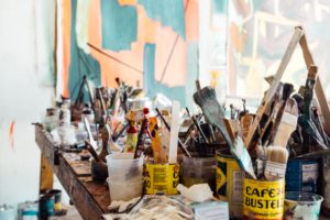 A stack of paint and brushes. Explore your creative side with these 5 Unique Careers in the art World.
