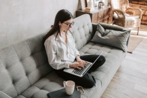 Woman sitting on her couch with her computer to improve her technical skills. Here's How to Improve Your Technical Skills