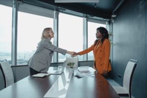 Two women shaking hands. Learn How to Negotiate Your Salary the right way.