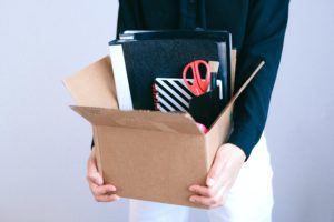 Woman packing up her stationary from the desk into a box after getting retrenched. Here are Ways to Earn Money When Unemployed