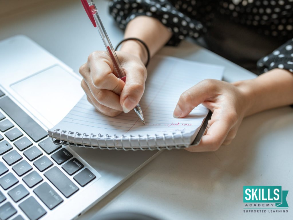 Woman making notes in a notepad with a red pen. Find out what not to include in your CV right here