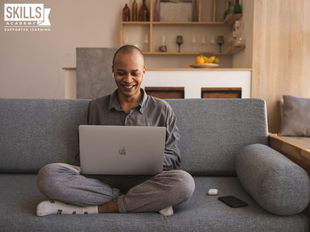 Man sitting on a couch with a laptop on his lap. Can you study National Diploma Courses Online? Fin out that and more right here.